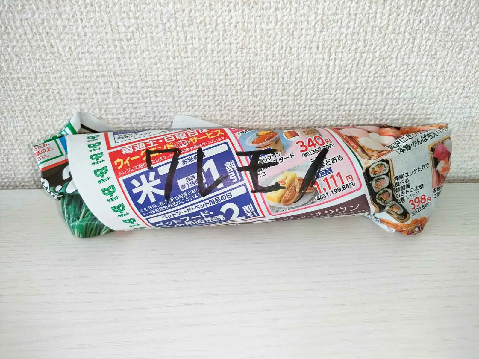 ミル付きの岩塩の瓶を新聞紙で包みワレモノと書いた状態