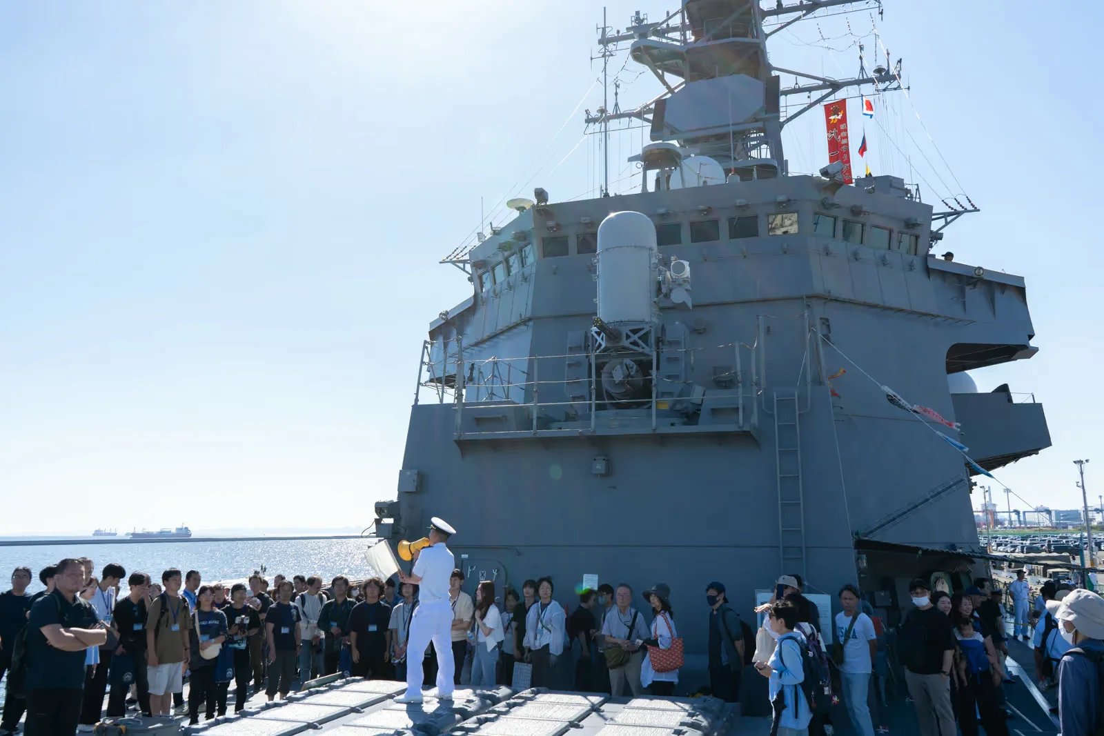 護衛艦ゆうだちの甲板で見学者に説明する海上自衛隊員